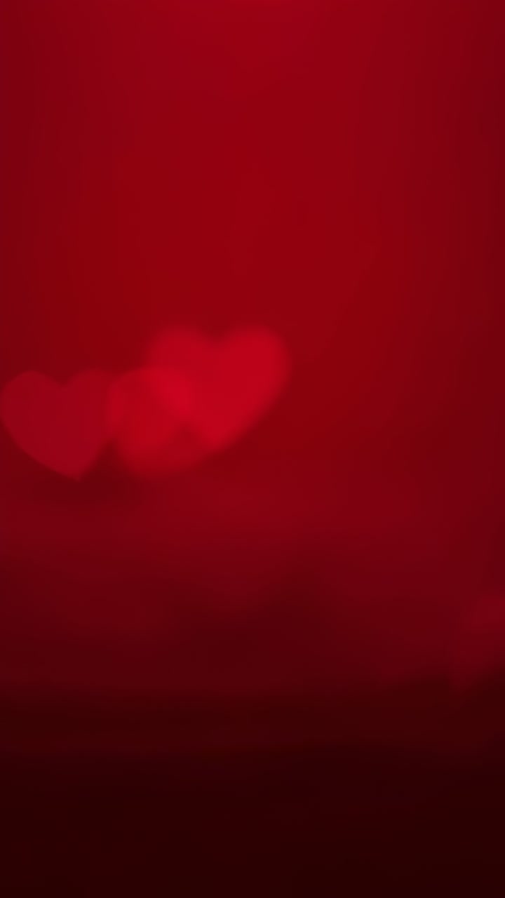 Video verticale: bokeh a cuore sfocato che si illumina dopo un leggero cambio di messa a fuoco in interni con gradiente rosso
