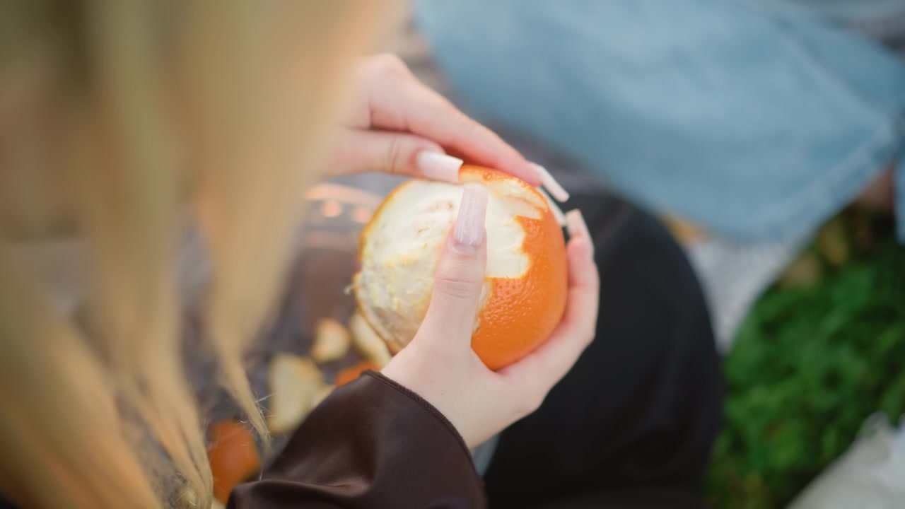 Jovem Mulher Descascando uma Laranja Fresca ao Ar Livre