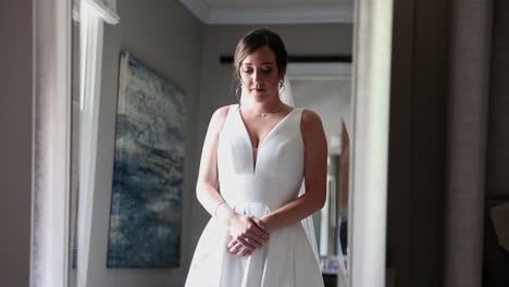 bride admires her wedding dress in a mirror