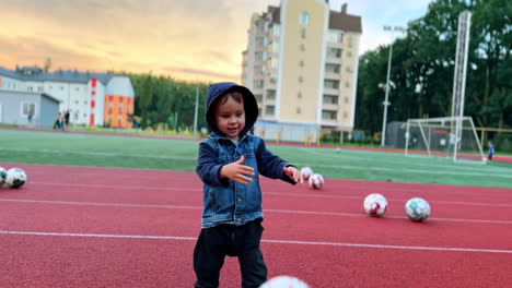 cute caucasian baby boy takes a ball from the ground. kid throws the ball and then picks another one.