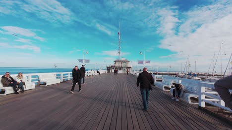 people walking along sopot pier on a sunny autumn day.