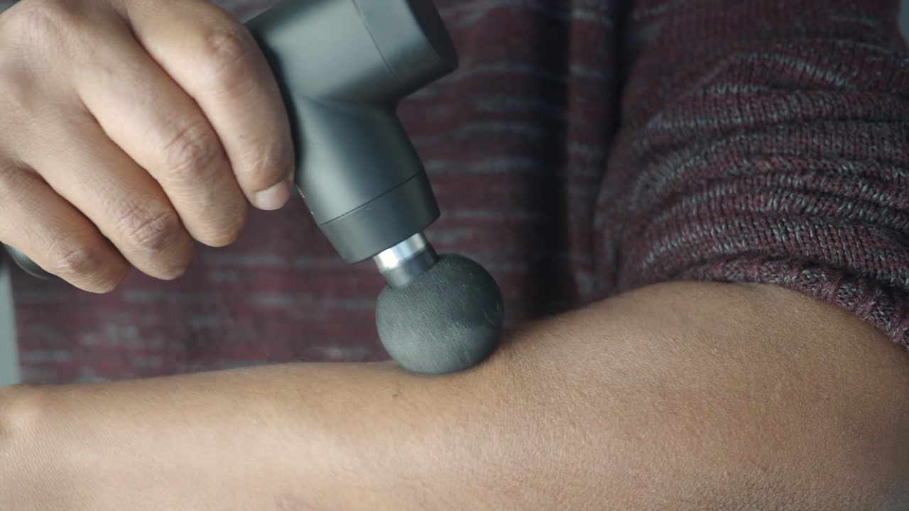 Person Using a Percussion Massage Gun on Their Arm