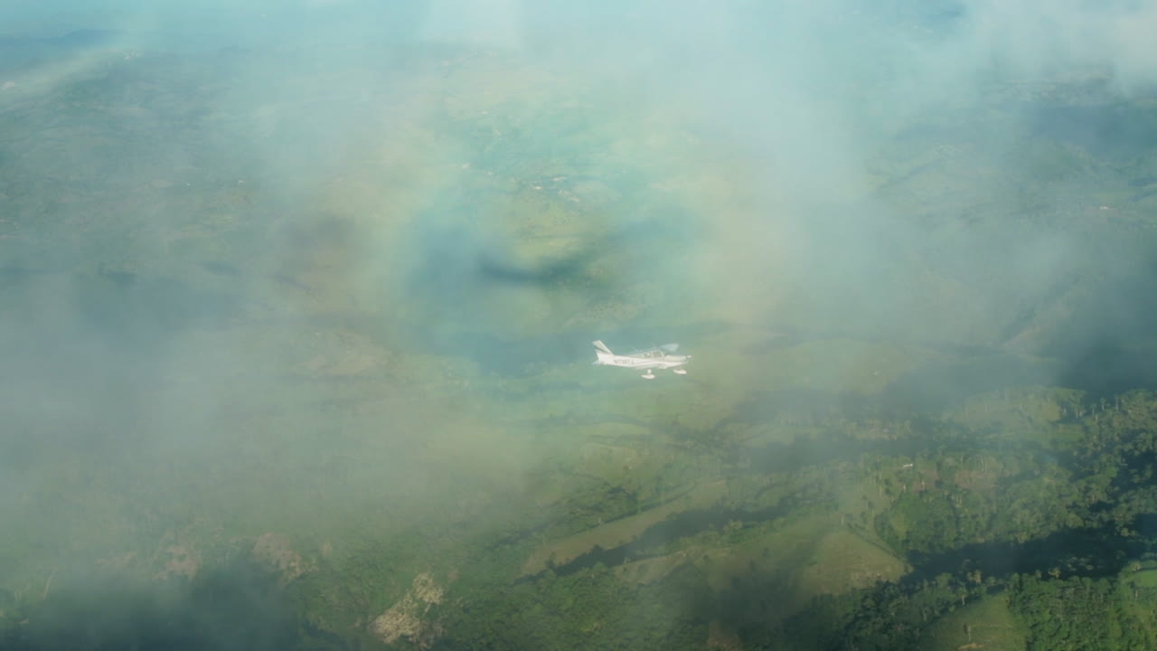 Luftoptagelse af et fly, der flyver gennem skyer med en halo-regnbue.