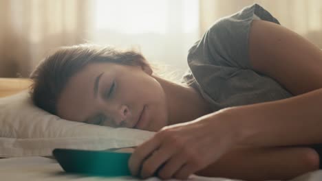 la mujer caucásica apaga el despertador y se despierta por la mañana.