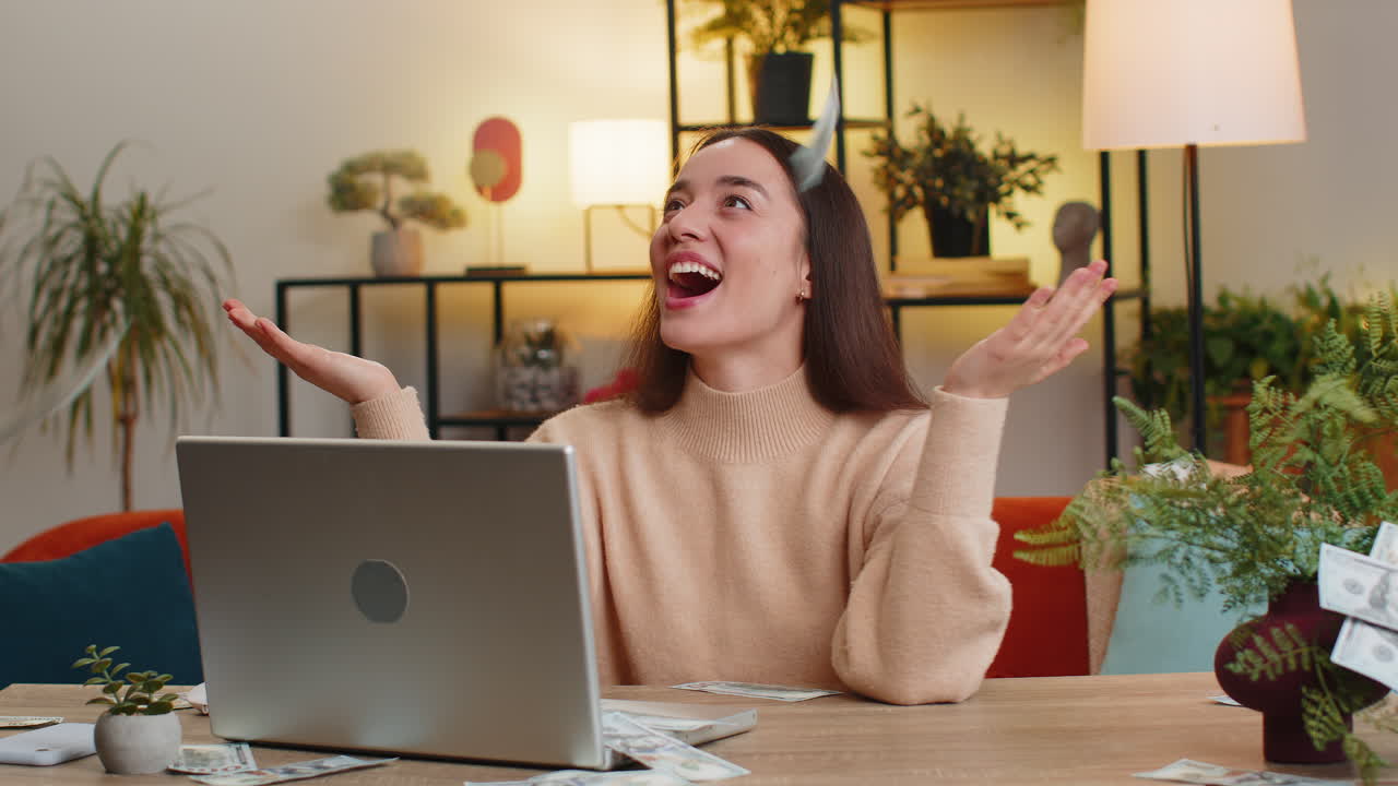 Money cash dollar rain falling on woman celebrating success winning laptop game lottery jackpot luck