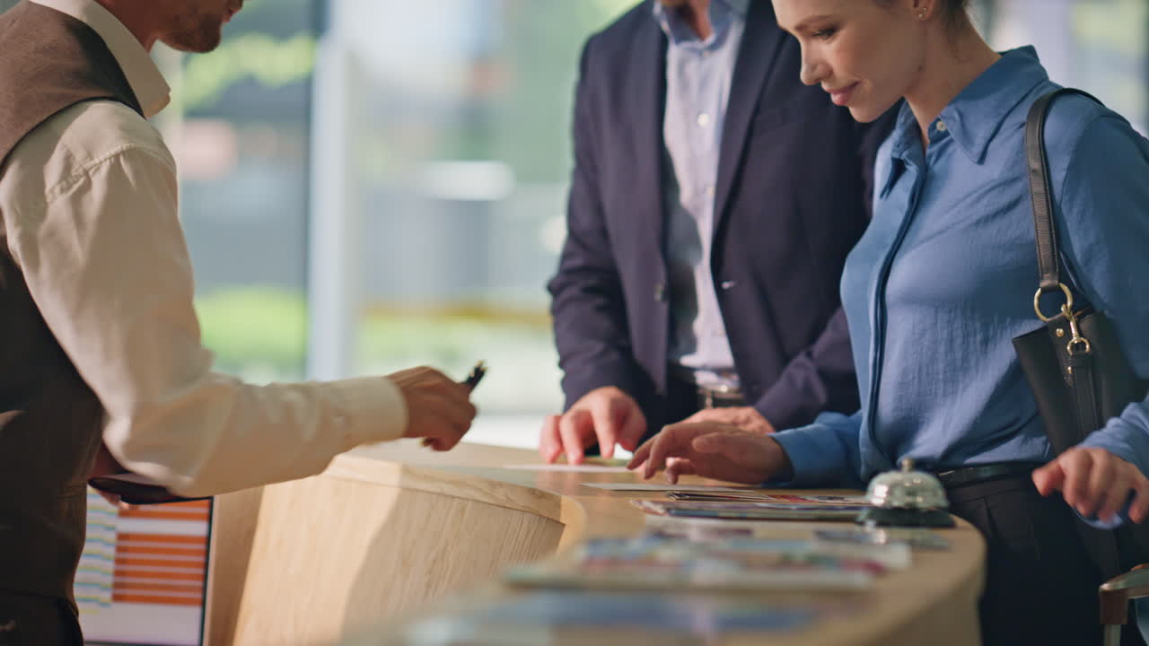 호텔 손님들이 책상 근처에서 여권을 주고 웃는 커플이 여행에 체크인합니다.