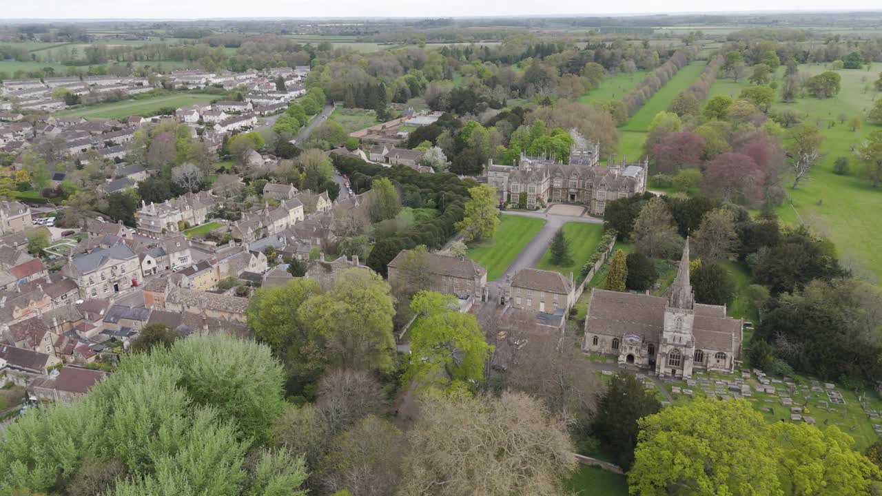 High aerial of Corsham Court manor and gardens merging into tree-lined high street and surrounding Wiltshire countryside, illustrating heritage town living