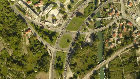 Bird-view-over-urban-area,-traffic-and-cars-driving,-green-nature-and-roads
