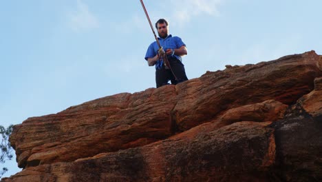 atleta ajustando su cuerda en la cintura mientras está de pie en el acantilado 4k