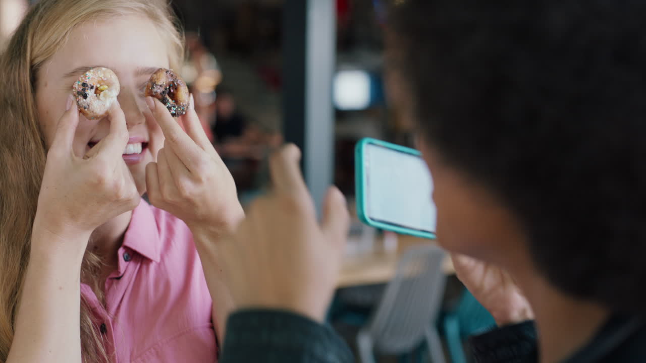 행복한 금발 여성이 도 ⁇ 과 포즈를 취하고 스마트폰을 사용하는 친구가 사진을 찍고 소셜 미디어 4k에서 주말을 함께 즐기고 있습니다.