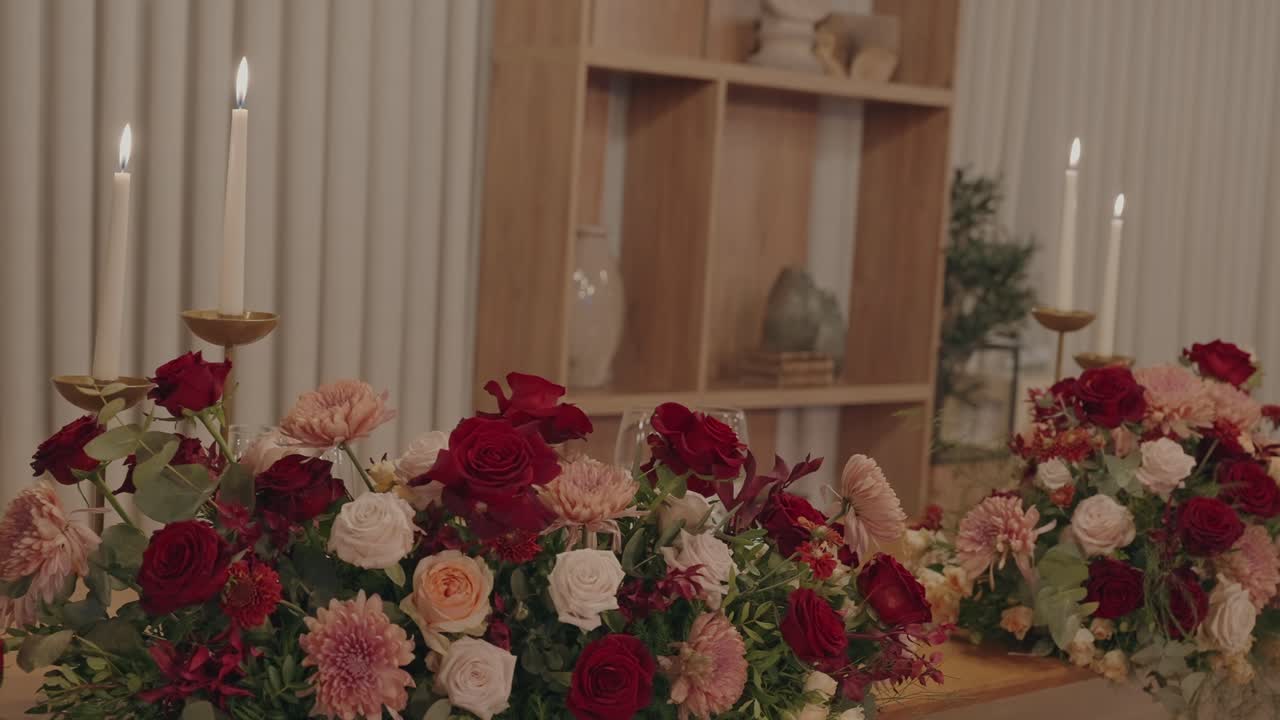 Vibrant red and blush floral arrangements paired with tall glowing candles