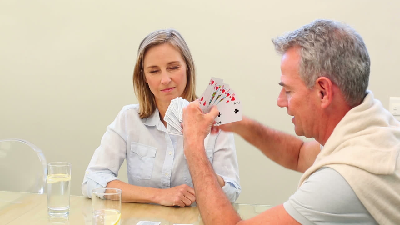una pareja madura jugando a las cartas juntos en la mesa.