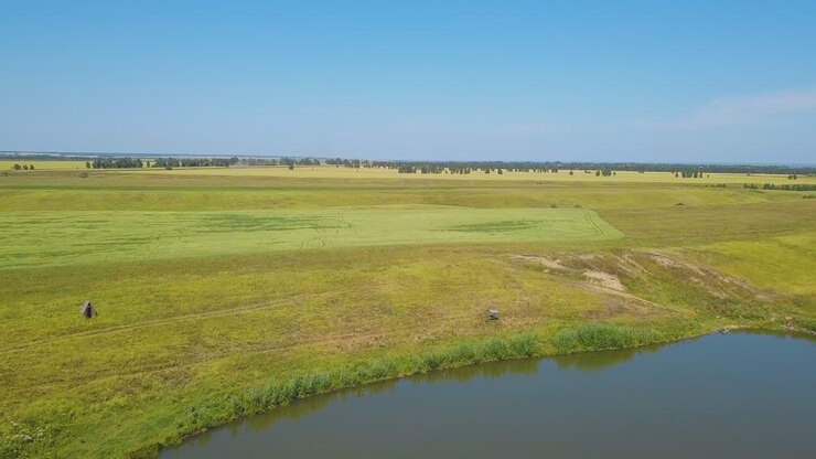 tranquil lake and field under boundless sky aerial panorama