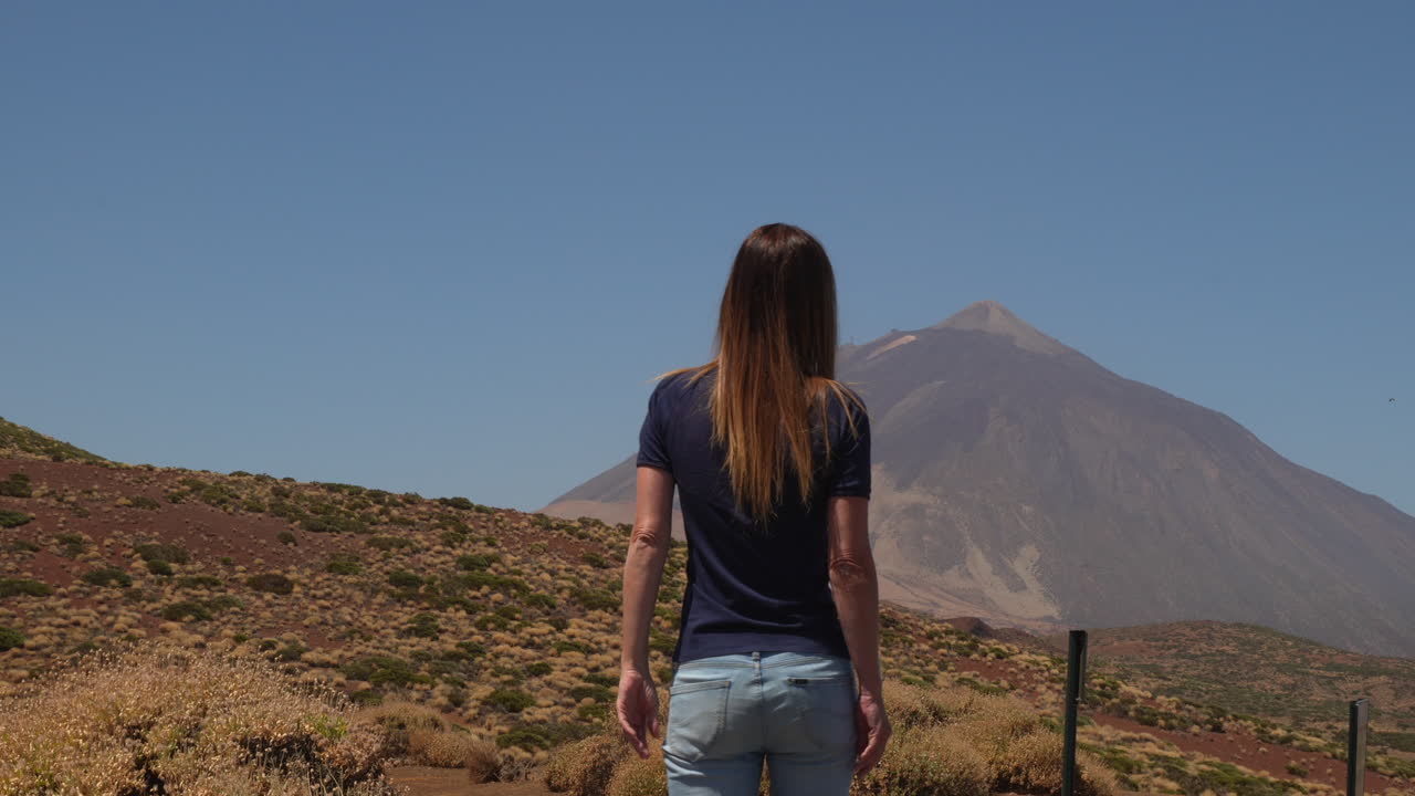 Female traveler looking at the Mount Teide volcano. The woman is enjoying the nature and tranquility of the Teide National Park
