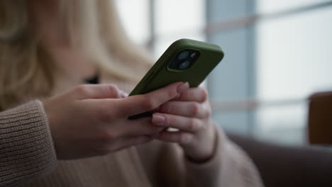 close-up of woman holding iphone and operating it, with soft focus on phone and hands, glass window visible in background, focus on mobile device interaction in modern setting