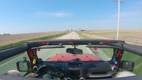 POV-while-a-couple-are-driving-on-a-country-road-with-roof-off-of-their-vehicle