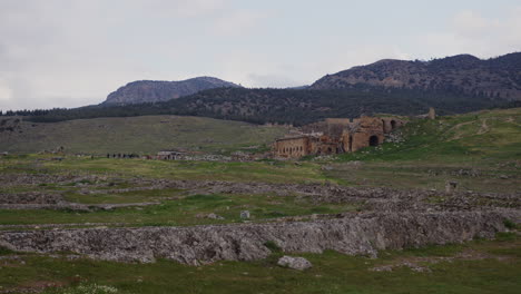 amplia fotografía del antiguo teatro con las cimas de las montañas detrás en hierápolis