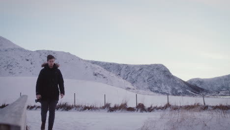 man with camera walks in snowy mountain scenery, active leisure in peaceful nature