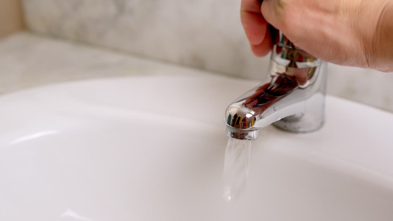 Hand opening and closing water faucet in bathroom sink