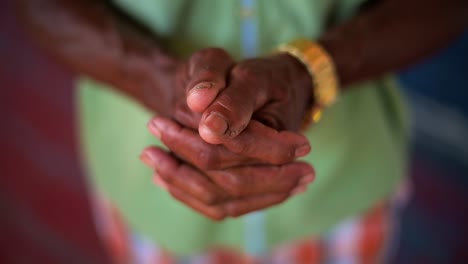 Elderly hands clasped together, slow-motion close-up in an Amazon rainforest village