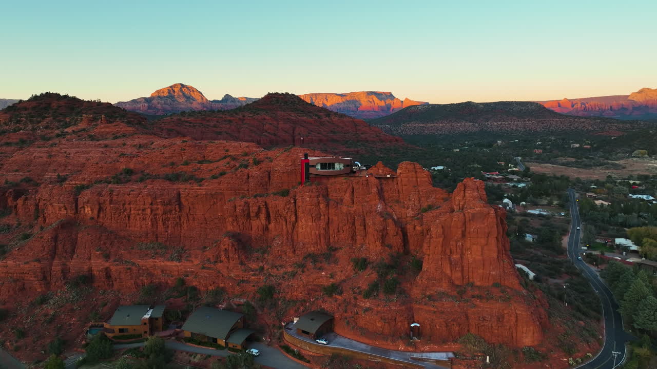 Aerial view of a modern house nestled in red rock formations at sunset