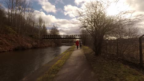 2 women take a walk along by the former industrial canal in stoke on trent, a poverty stricken area featuring many factories in ruins along by the canal