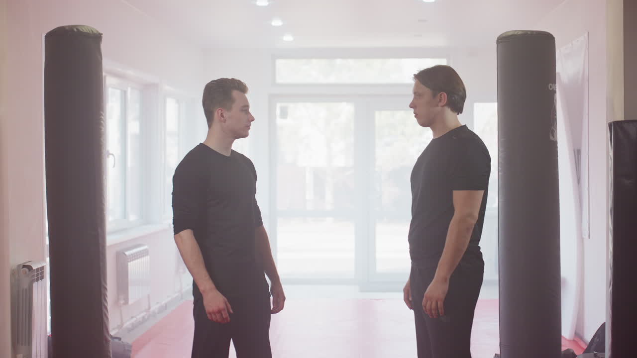 Two fighters in sportswear shake hands inside training gym, symbolizing respect, teamwork, discipline, unity, camaraderie, trust, sportsmanship, preparation, focus, strength, and honor before combat