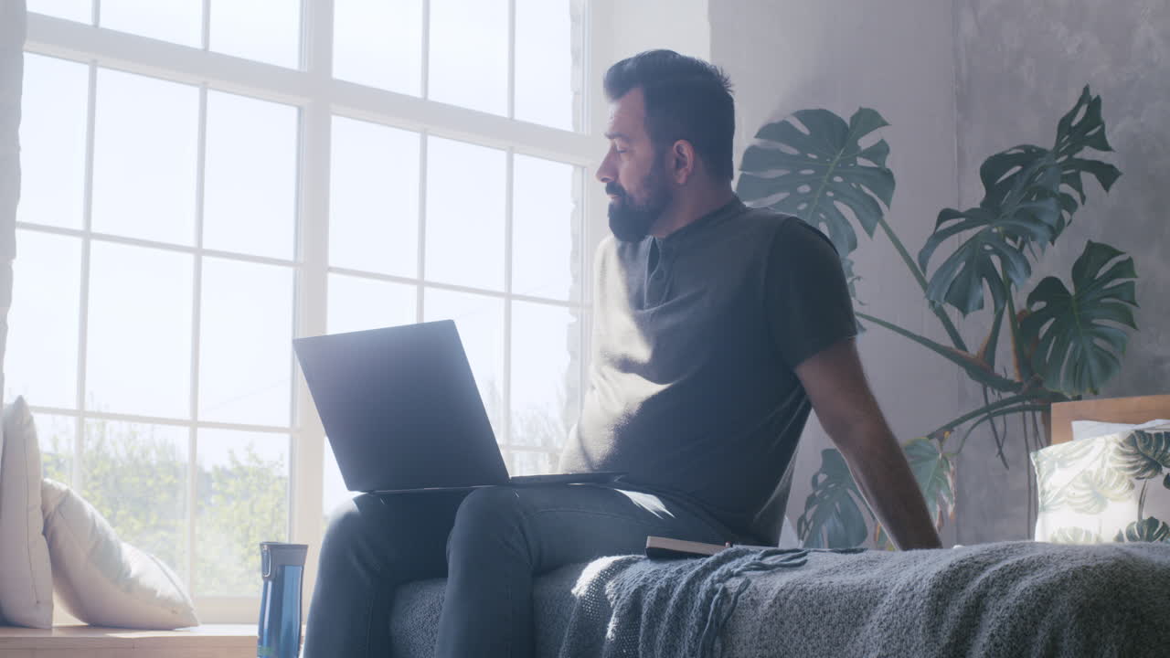 hombre trabajando en una computadora portátil en el dormitorio