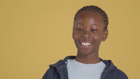 Studio-Portrait-Of-Young-Boy-Smiling-And-Laughing-Against-Yellow-Background