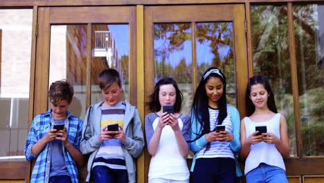 group of school friends using mobile phone outside school