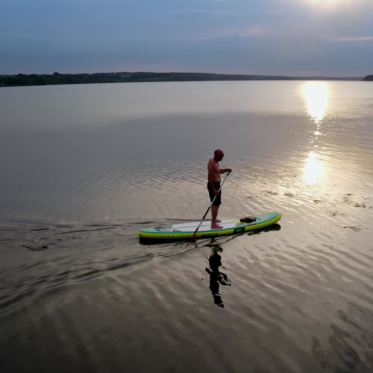 Man standing on paddle board. Aerial view of man paddling on SUP board on large river