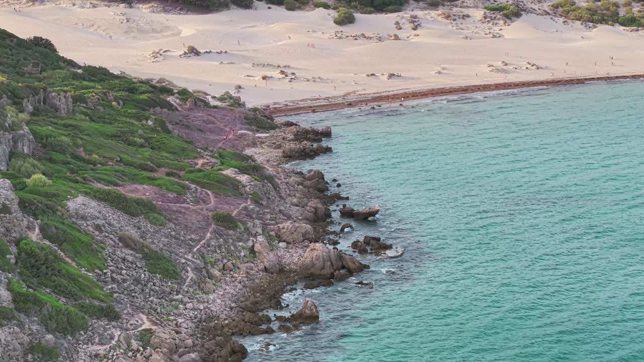 Drone view of Bolonia sand dunes in Cádiz, Spain, showing golden sandy beach, rocky coastline, and turquoise sea