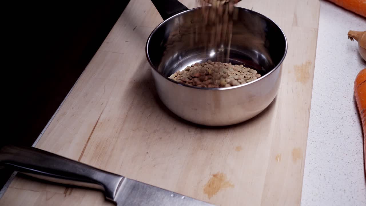 요리사가 요리를 시작하려고 냄비에 녹색 렌즈콩을 붓고 있습니다.