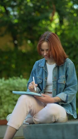 woman drawing on tablet in park