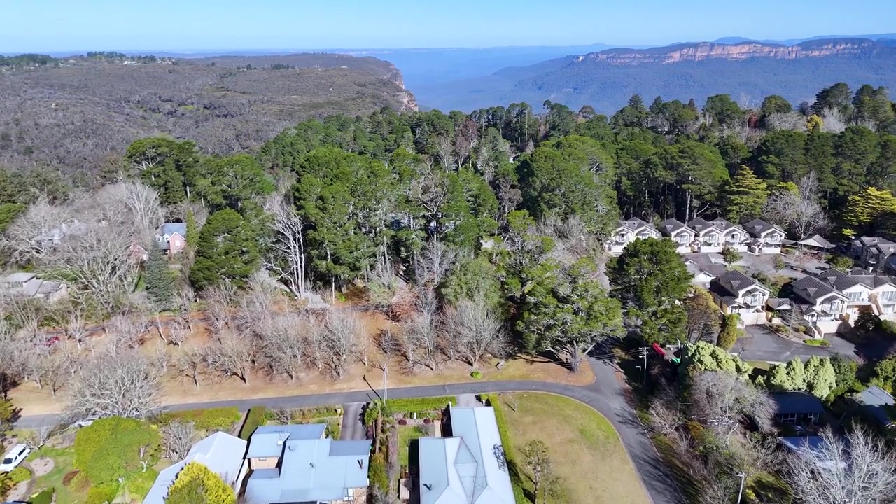 Cảnh quay flycam những ngôi nhà ngoại ô và cây cối xanh tươi gần vách núi ở Wentworth Falls, Úc.