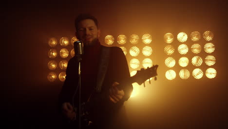 Handsome-guitarist-singing-microphone-in-night-club.-Vocalist-playing-guitar.