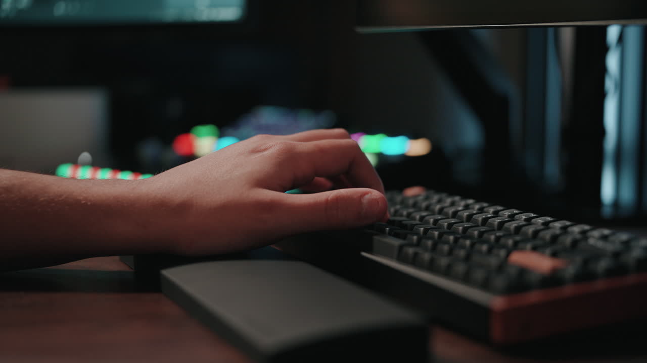 Person Typing on a Keyboard at a Computer Workstation at Night