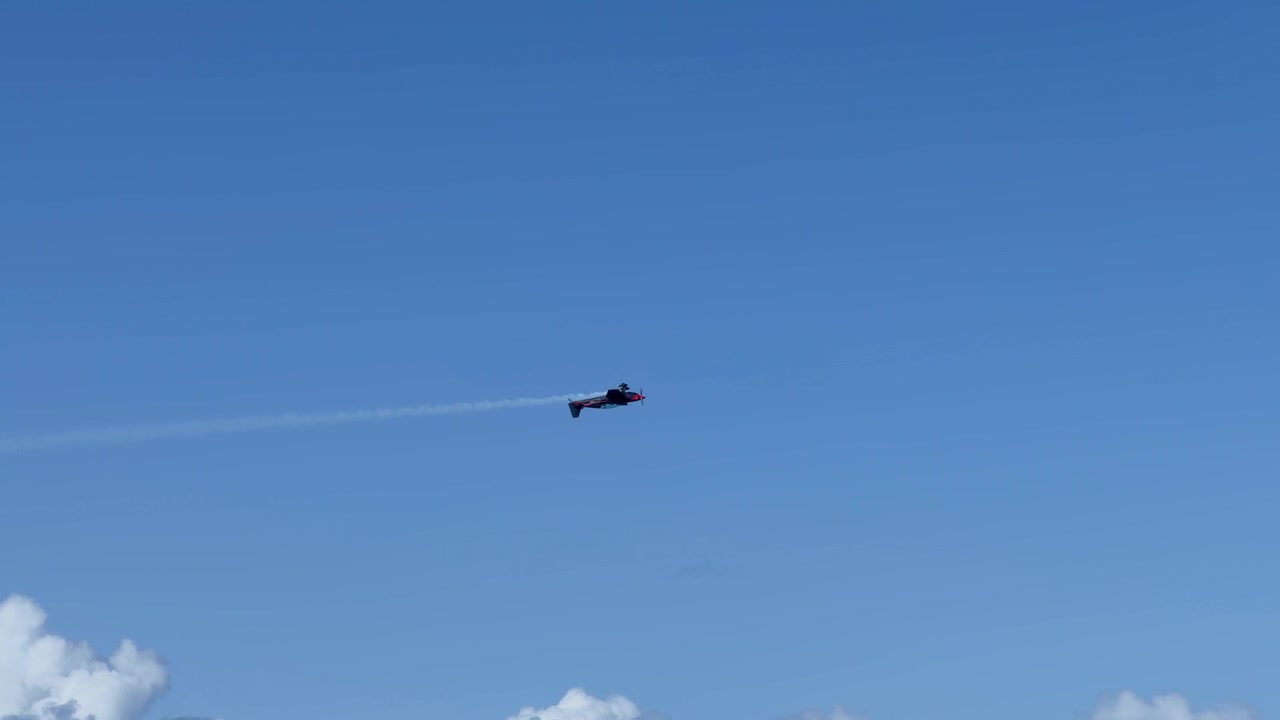 Kunstflyvningspropelfly flyver hen over klar blå himmel og efterlader et hvidt røgspor over Gold Coast