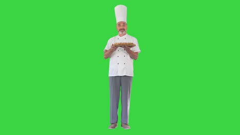 chef feliz olendo una pizza y ofreciéndolo a usted en una pantalla verde, llave de croma