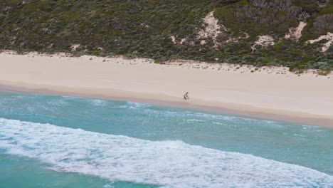 Couple-walking-along-the-beach-at-sunset-in-Margaret-River,-Western-Australia