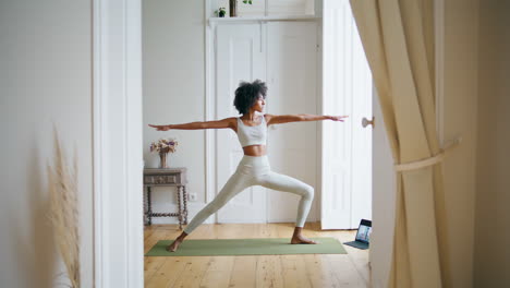 calm lady practicing yoga home. african girl stretching body at white interior