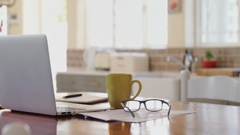 portátil con documentos, anteojos y taza de café en una mesa 4k