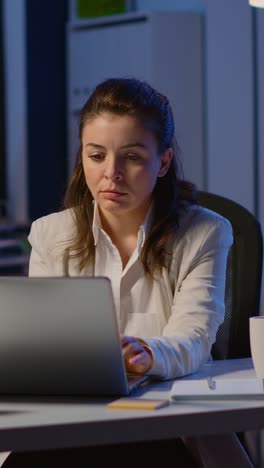 vertical video: stressed businesswoman suffering from headache at work doing overtime
