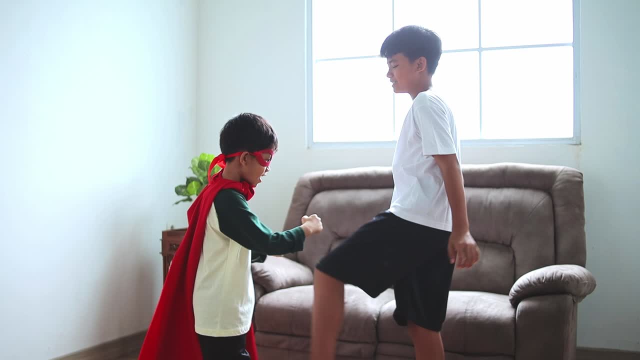 Energetic Brothers playfully fighting with superhero outfits at home