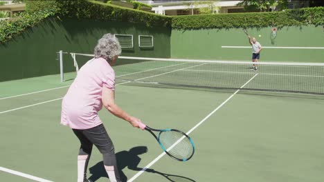 caucasian senior couple paying a game of tennis on an outdoor court in the sun