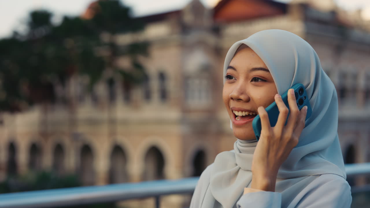 Young Muslim woman talking on a smartphone outdoors