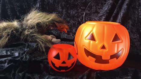 brazo de monstruo agarra un cubo de calabaza feliz de halloween y lo saca del marco