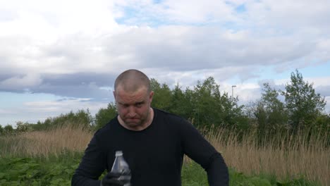 a drunk polish man drinking homemade alcohol outdoors - medium shot