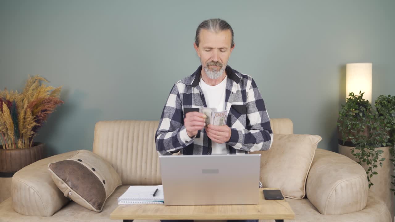노트북을 보고 돈을 세는 남자.
