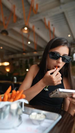 young woman eating sweet potato fries in a cafe